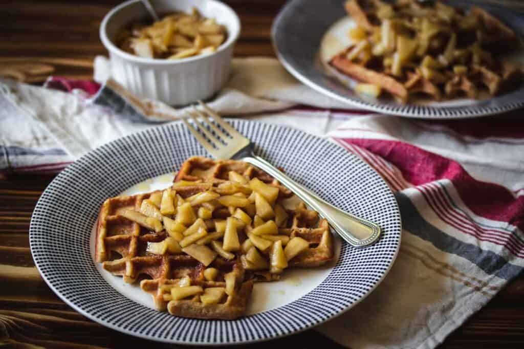 two plates of gluten free applesauce waffles with apple topping