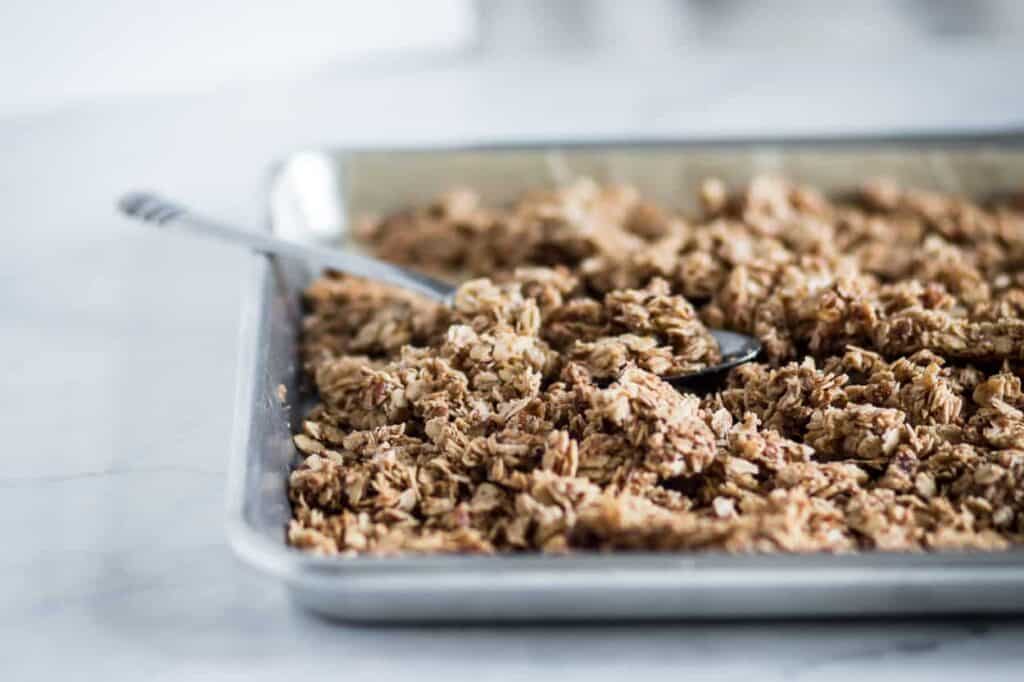 gluten free salty & sweet granola on a baking sheet with a spoon