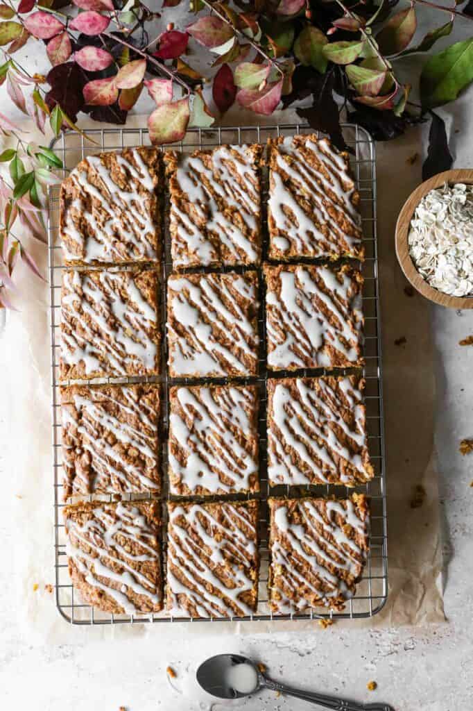 a gluten free pumpkin oatmeal cake cut into slices on a cooling rack with vanilla glaze drizzled over the top