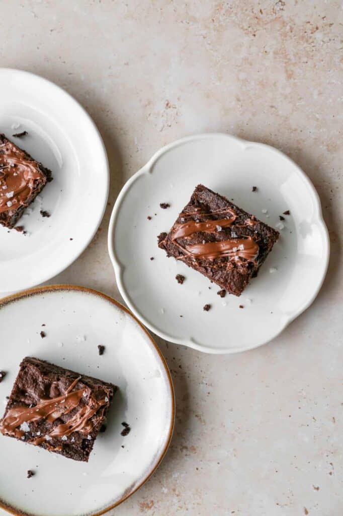 three plates with gluten free triple chocolate brownies that are drizzled in milk chocolate