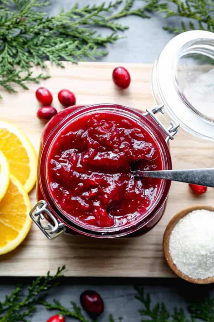 a jar of cranberry jam with orange slices and fresh cranberries