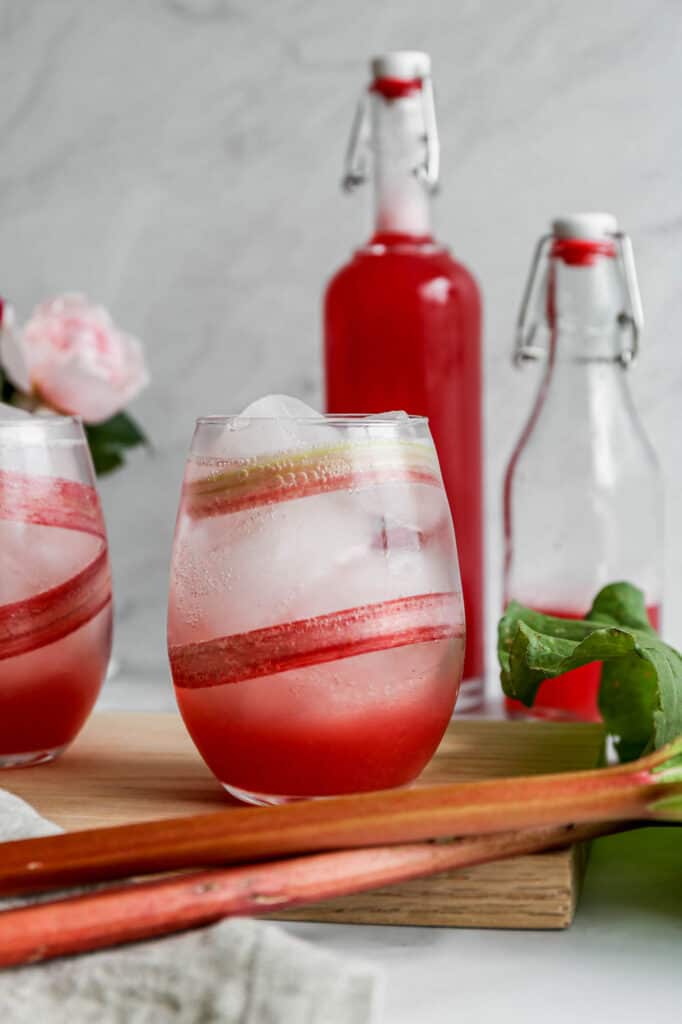 a glass lined with a slice of rhubarb and ice with a instant pot rhubarb simple syrup and sparkling water