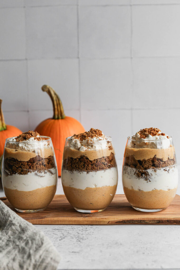 a glass of gluten free pumpkin gingersnap parfait with layers of pumpkin spice mousse, homemade whipped cream and crumbled gluten free gingersnap cookies