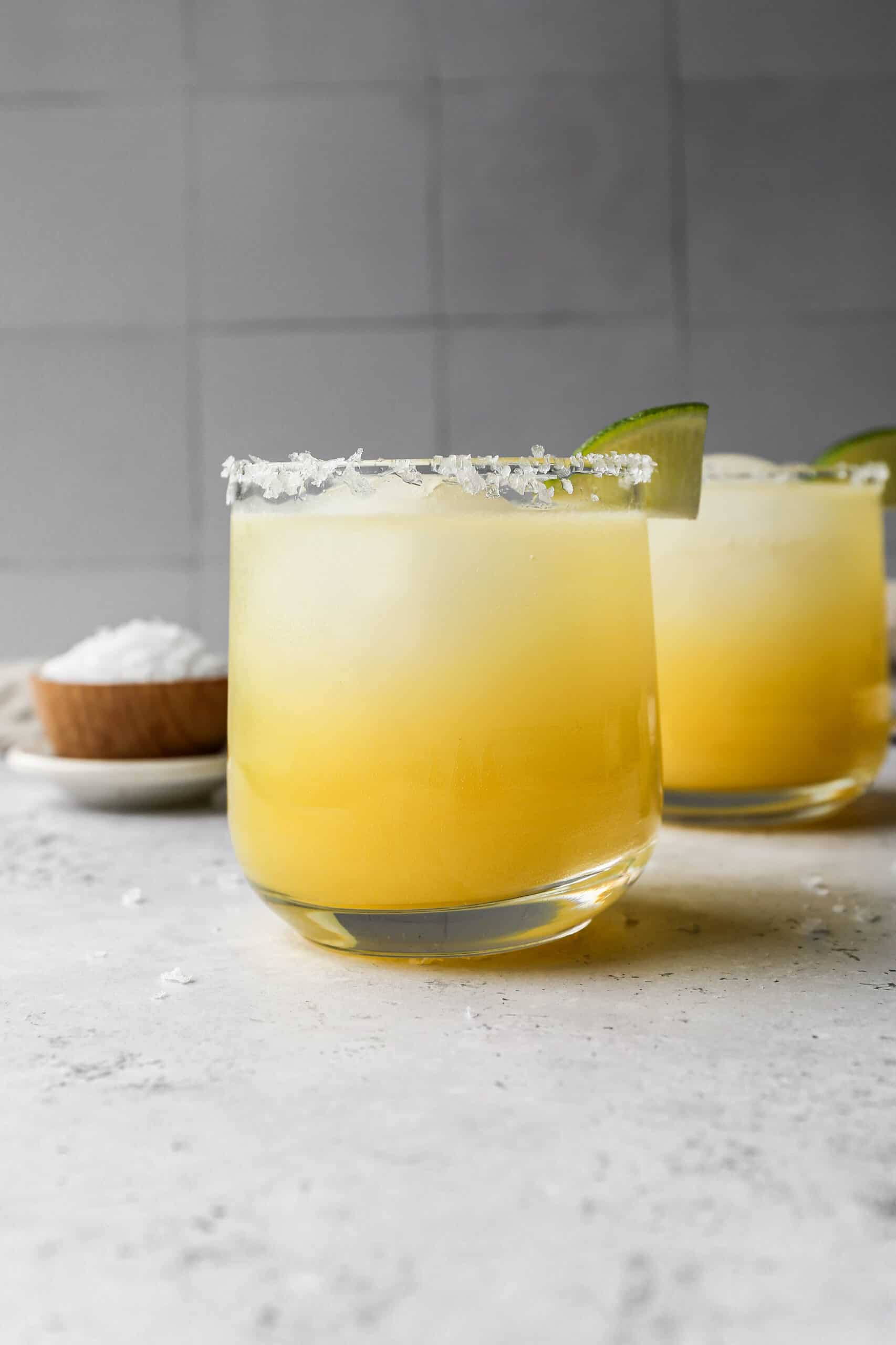 a glass of classic margarita mocktail with salt and lime on the rim.