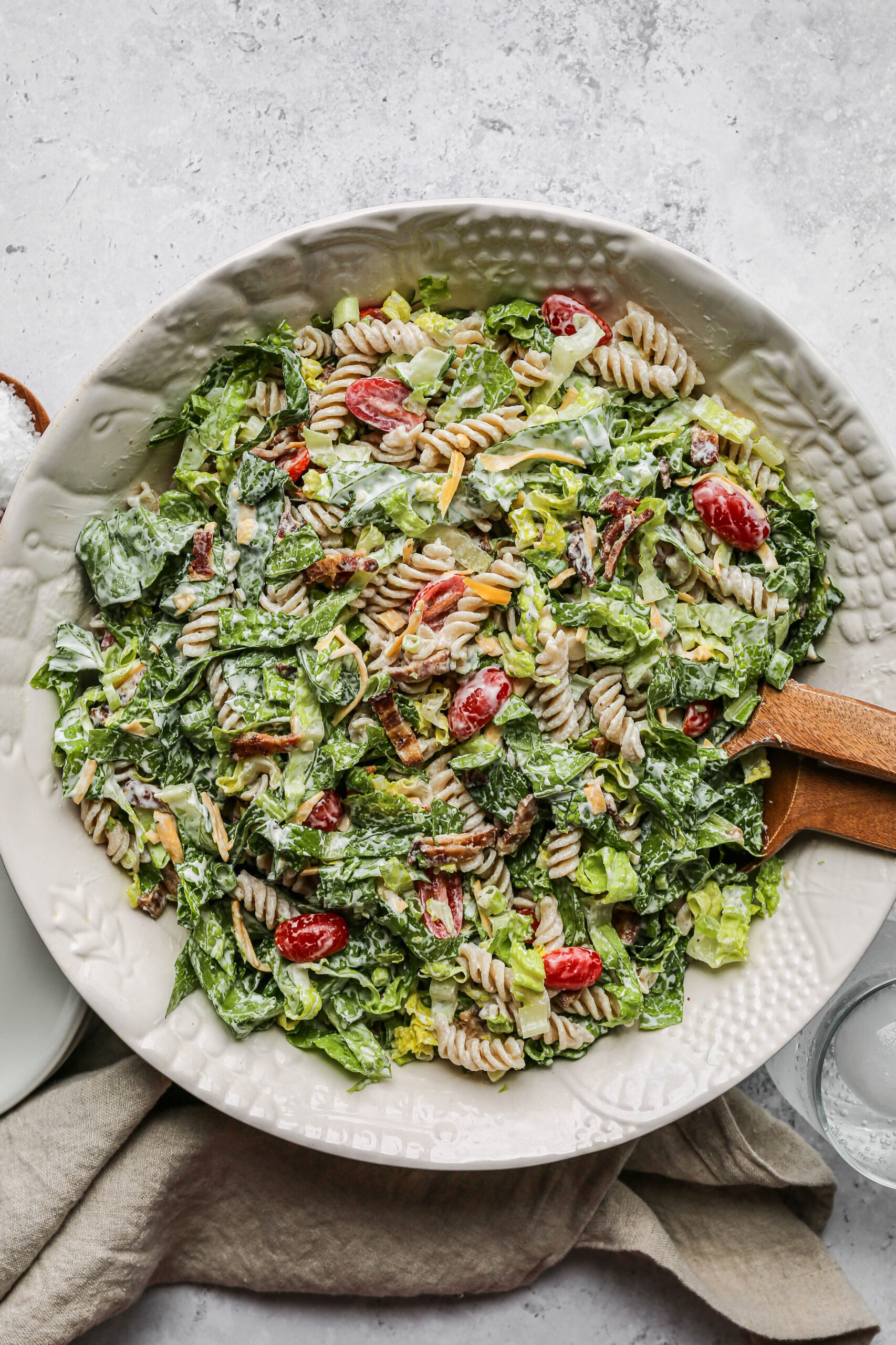 a large white serving bowl of gluten free BLT pasta salad with wooden serving spoons.