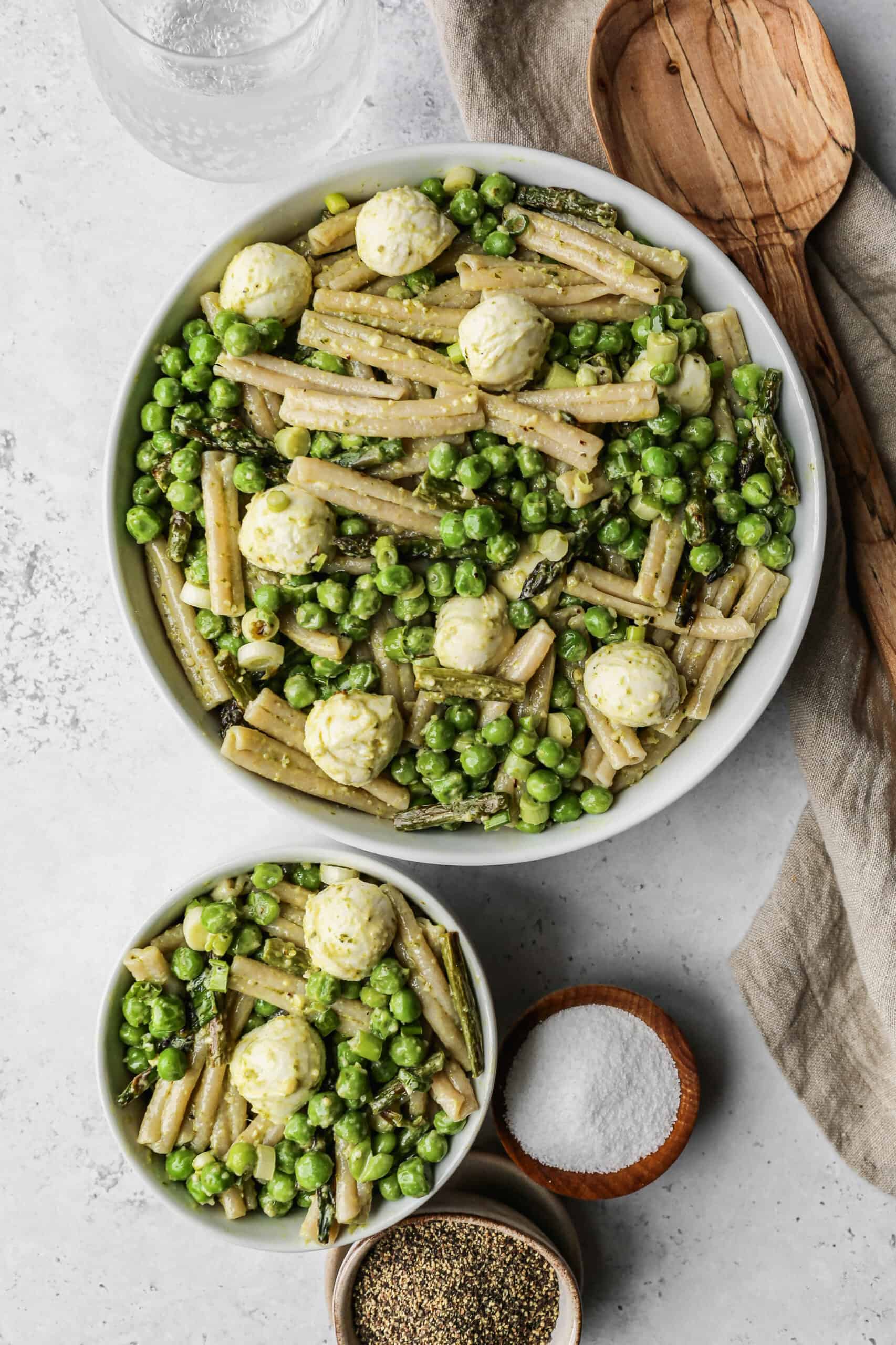 a white bowl of gluten free green goddess pasta salad next to a wooden serving spoon.