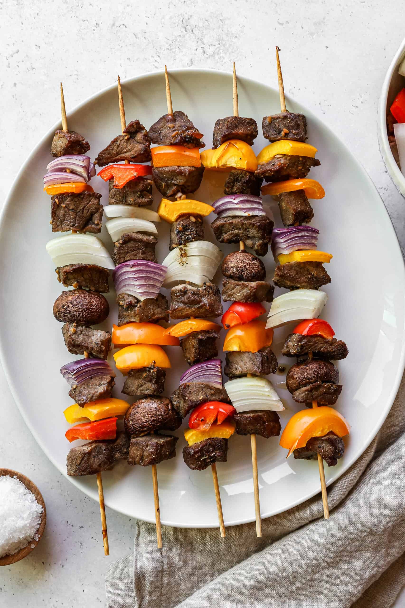 a white platter with oven baked marinated steak kabobs on it.