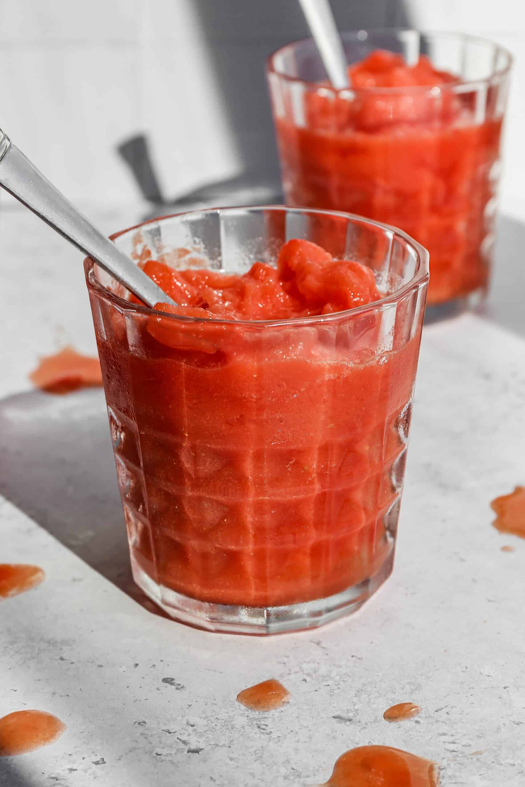 a glass tumbler of easy frozen watermelon margarita mocktail with a silver spoon in it.