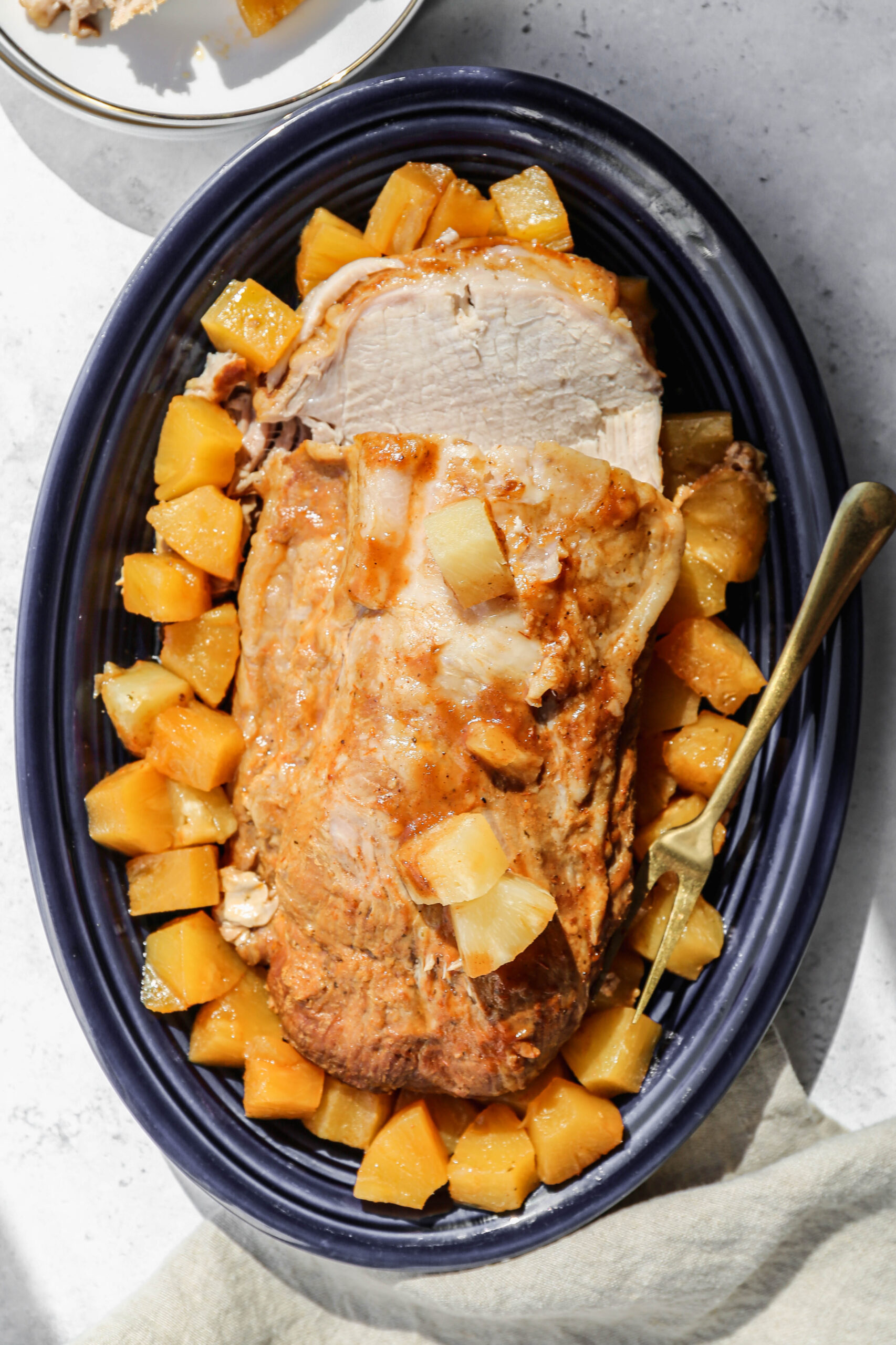 a blue platter with a slow cooker Hawaiin pork tenderloin surrounded by cooked pineapple chunks.