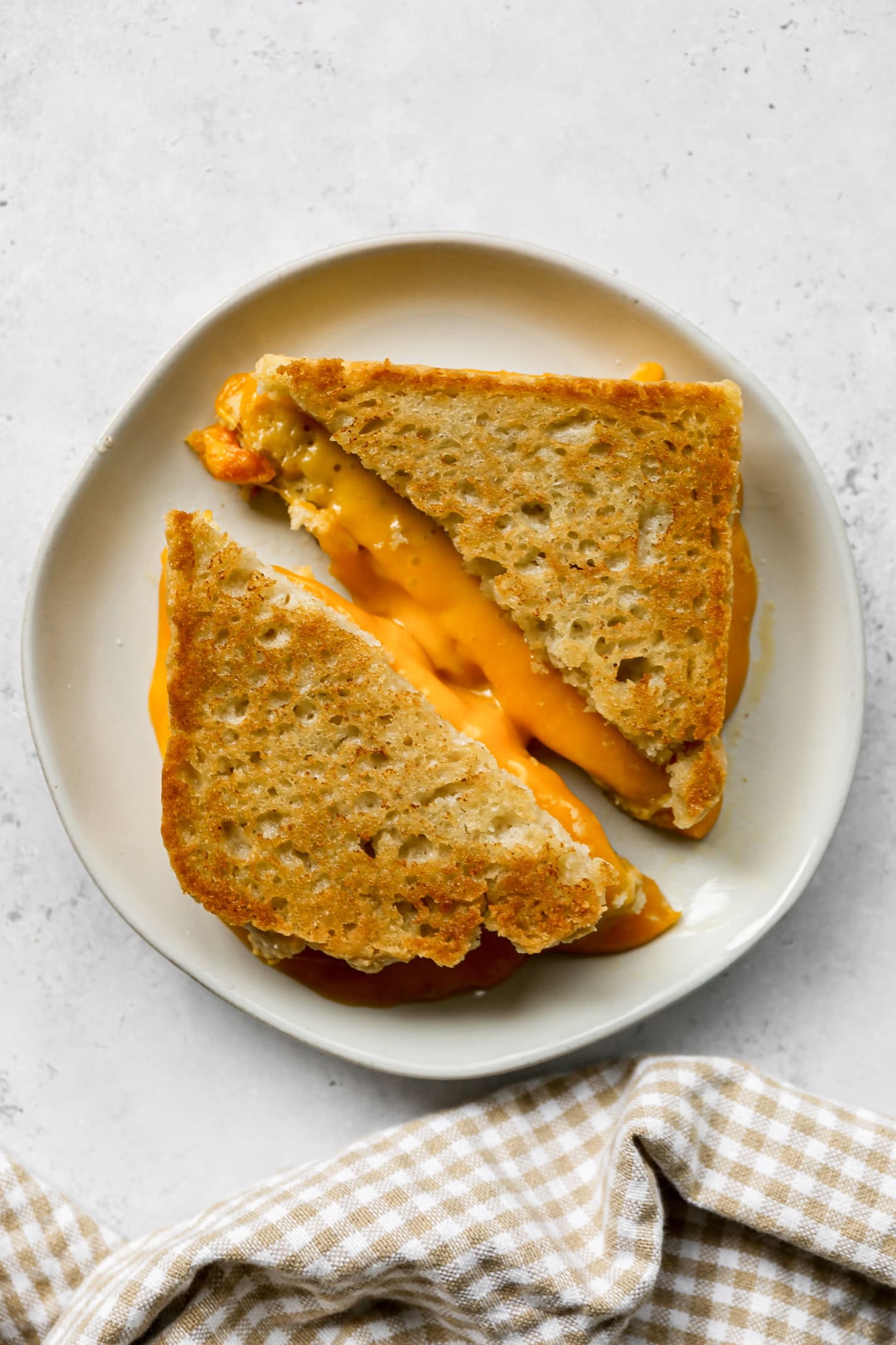 a grilled cheese sandwich made out of gluten free sourdough sandwich bread on a white plate