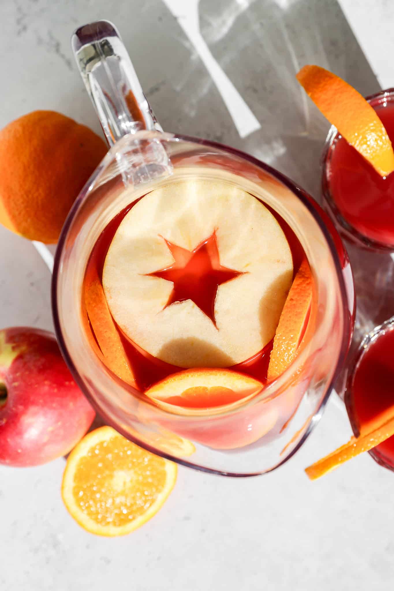an overhead view of the autumn harvest punch in a clear pitcher with apple and orange slices on top