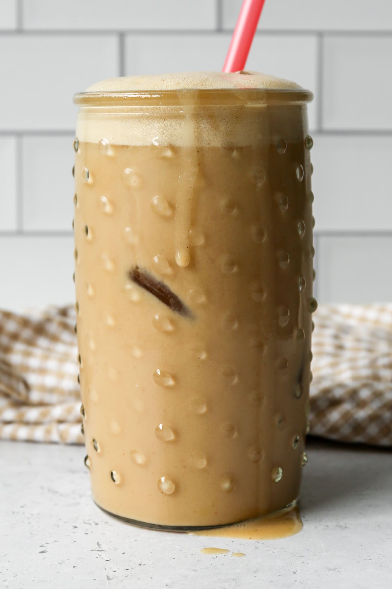 a clear hobnail drinking glass of high protein vanilla iced espresso over ice dripping down the side