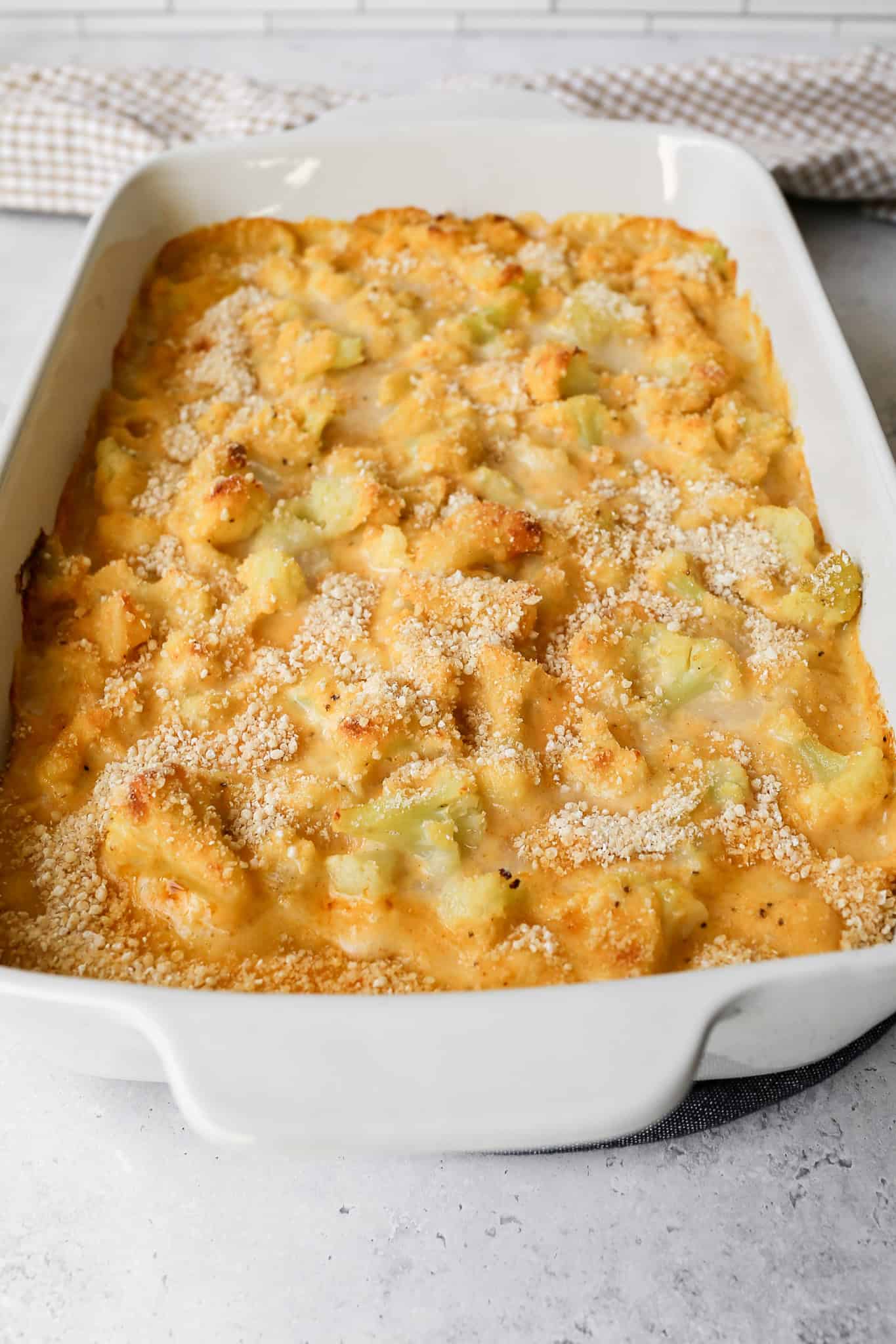 a white ceramic 9x13 baking dish of cheesy cauliflower casserole