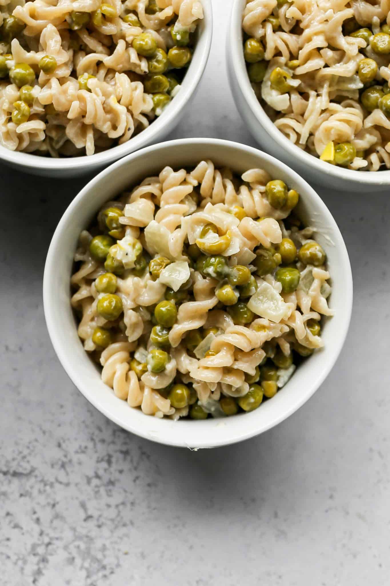 three white bowls of gluten free creamy peas and pasta