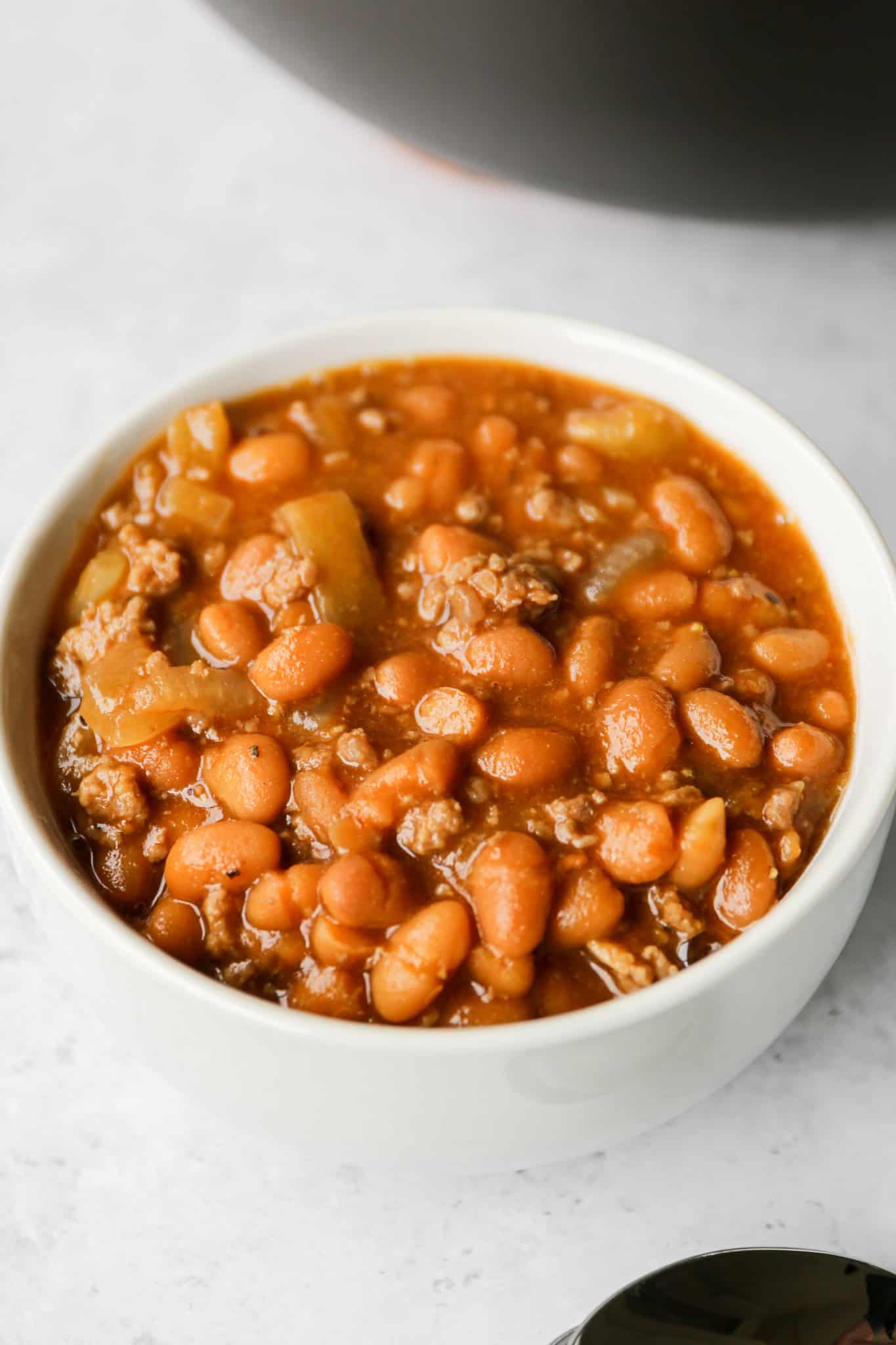 a white bowl of gluten free baked beans with ground beef