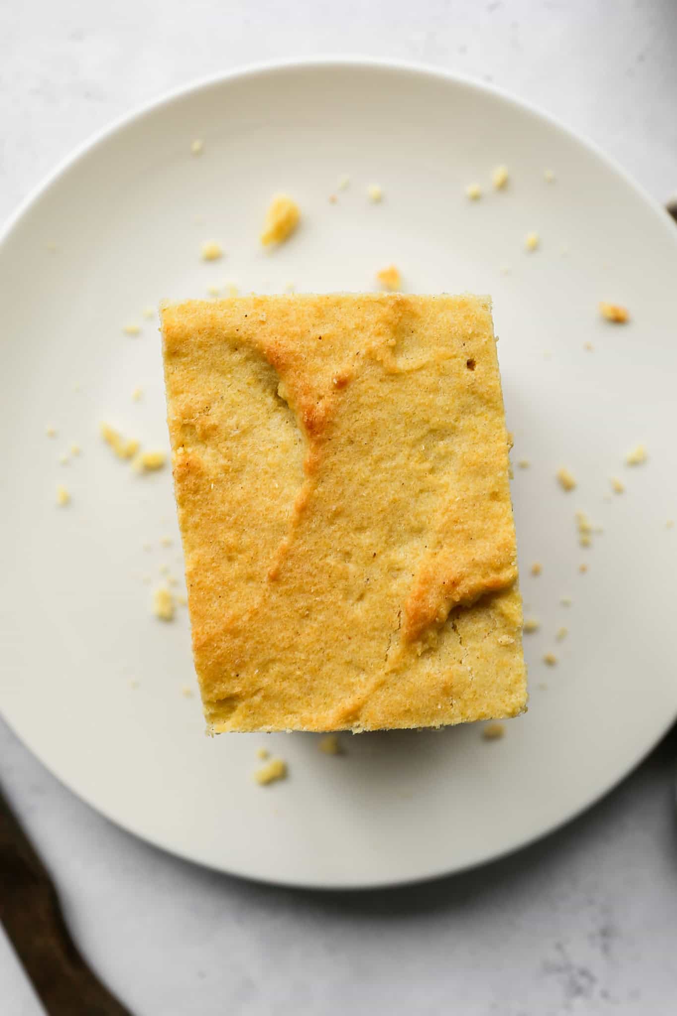 a piece of gluten free buttermilk cornbread on a cream plate